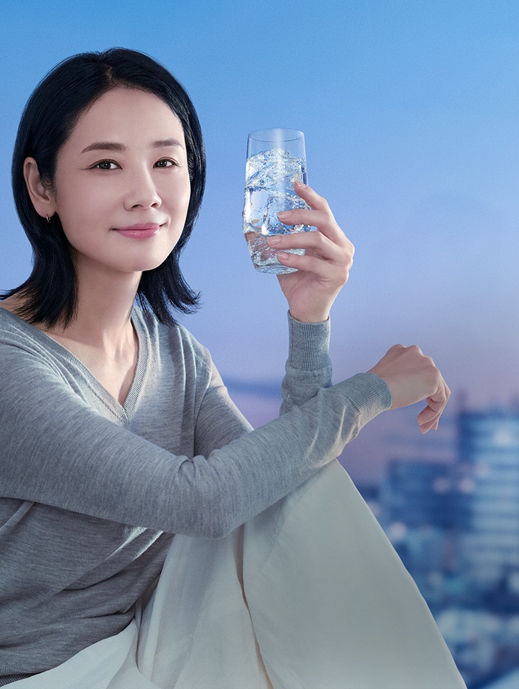 氷の入ったグラスを片手に持つ女性